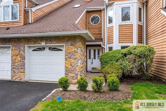 view of front of property with stone siding, roof with shingles, and driveway