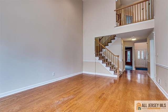 entrance foyer with stairway, wood finished floors, baseboards, and a high ceiling