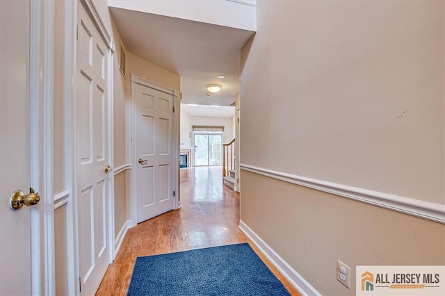 hallway featuring light wood finished floors and baseboards