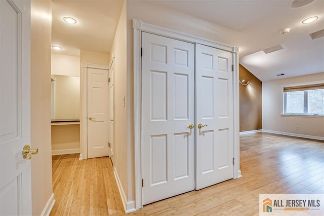 corridor featuring light wood finished floors and baseboards