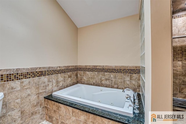 full bath featuring a jetted tub and lofted ceiling