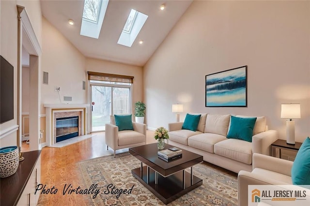 living area featuring high vaulted ceiling, wood finished floors, a high end fireplace, a skylight, and recessed lighting