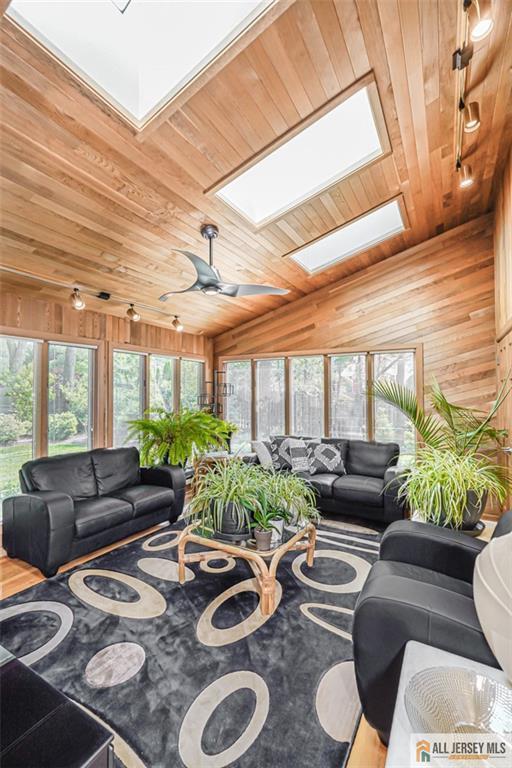 5 Leighton Dr, East Brunswick, NJ 08816 - living room with a skylight, wooden walls, wood ceiling, a ceiling fan, and vaulted ceiling