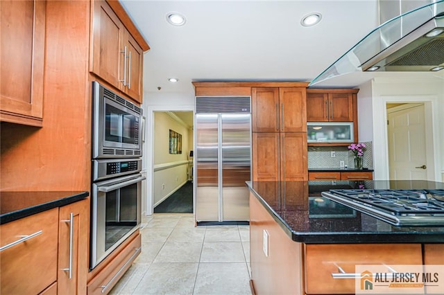 5 Leighton Dr, East Brunswick, NJ 08816 - kitchen with built in appliances, brown cabinetry, dark stone countertops, light tile patterned floors, and tasteful backsplash