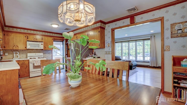 230 Raritan St, South Amboy, NJ 08879 - dining space with wallpapered walls, ornamental molding, a chandelier, and light wood-style floors