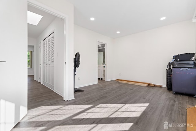 interior space with a skylight, baseboards, recessed lighting, and wood finished floors