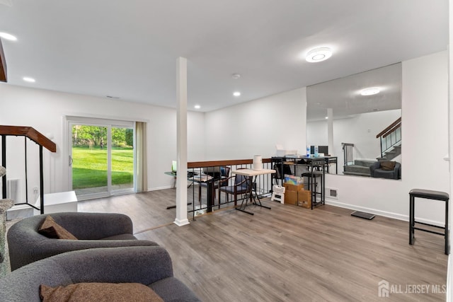 living area featuring baseboards, visible vents, wood finished floors, and stairway