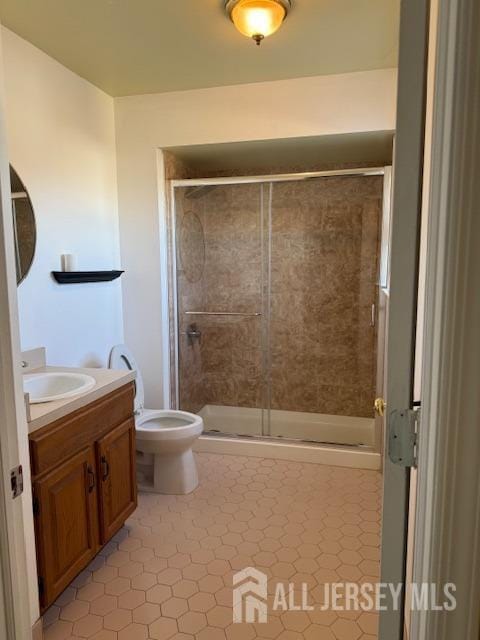 bathroom featuring toilet, a stall shower, tile patterned floors, and vanity