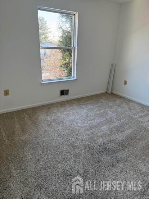 spare room featuring carpet, visible vents, and baseboards