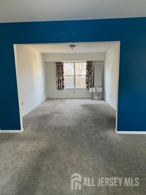 carpeted empty room featuring baseboards