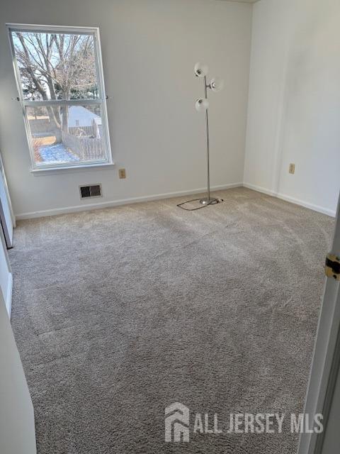 carpeted spare room featuring visible vents and baseboards