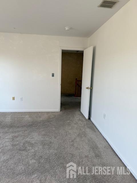 carpeted empty room with visible vents and baseboards