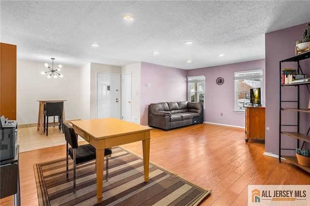 dining room featuring light wood-type flooring, a notable chandelier, and a textured ceiling