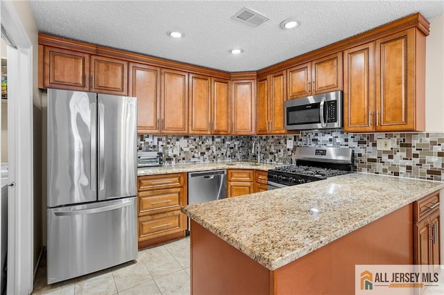 kitchen featuring light stone counters, light tile patterned floors, backsplash, appliances with stainless steel finishes, and sink