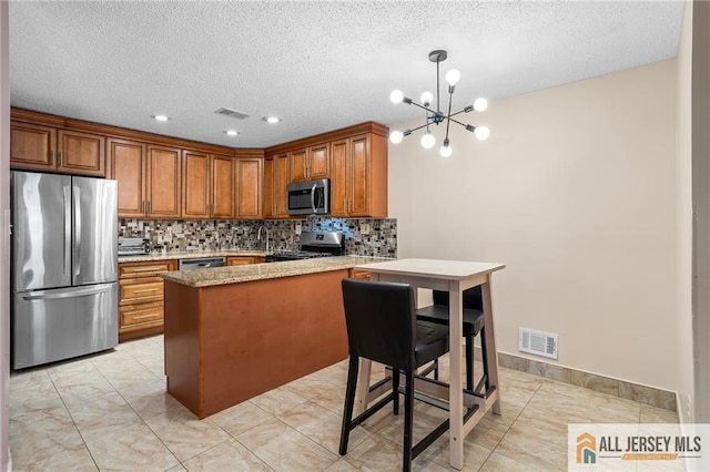 kitchen with stainless steel appliances, hanging light fixtures, kitchen peninsula, a notable chandelier, and light stone counters