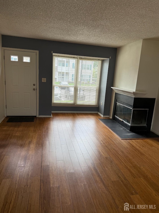 425 Northam Dr, North Brunswick, NJ 08902 - unfurnished living room with a glass covered fireplace, a textured ceiling, and wood finished floors