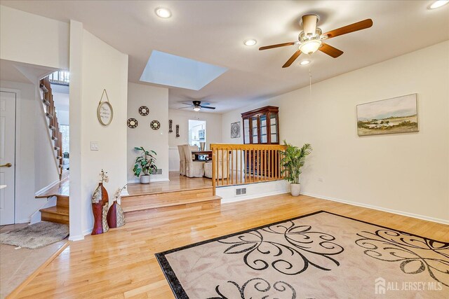 entryway with ceiling fan, a skylight, and hardwood / wood-style flooring