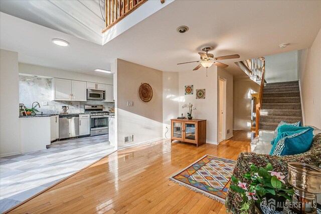 living room featuring ceiling fan, sink, and light hardwood / wood-style flooring