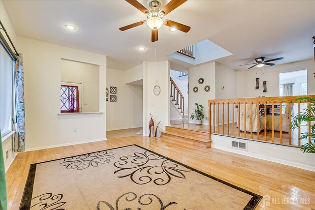 interior space with hardwood / wood-style flooring, a skylight, and ceiling fan