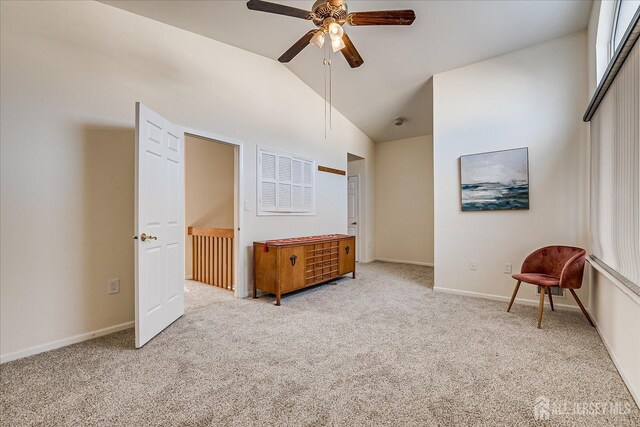 interior space featuring ceiling fan, light colored carpet, and vaulted ceiling