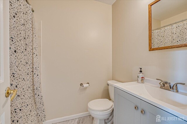 bathroom with toilet, vanity, and a shower with curtain