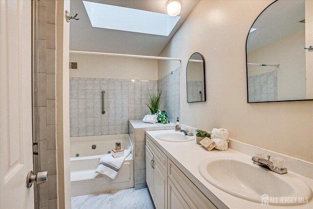 bathroom with a tub to relax in, vanity, and a skylight