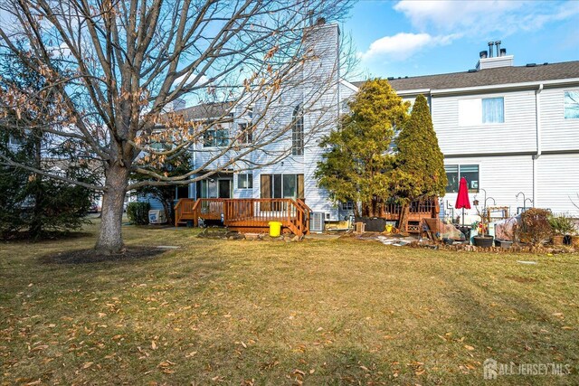 rear view of property featuring a lawn and a deck