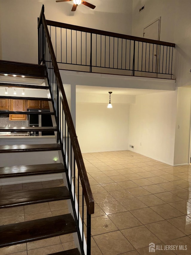 stairs with a high ceiling, tile patterned floors, and ceiling fan