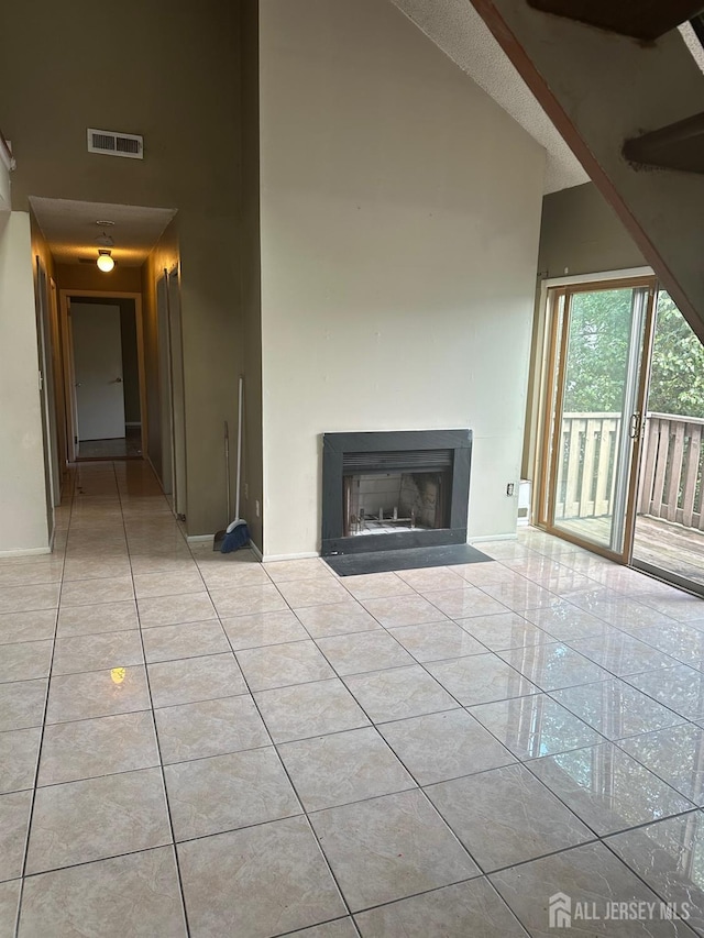 unfurnished living room with light tile patterned flooring and high vaulted ceiling