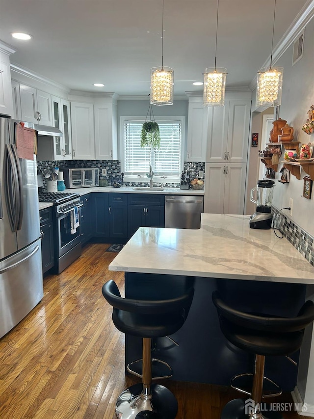 741 Bound Brook Rd, Dunellen, NJ 08812 - kitchen featuring appliances with stainless steel finishes, blue cabinets, a breakfast bar area, decorative backsplash, and crown molding