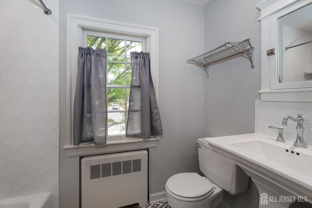 bathroom featuring a sink, toilet, radiator, baseboards, and decorative backsplash