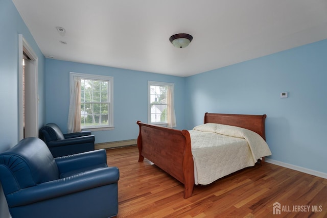 bedroom featuring baseboards, baseboard heating, and light wood-style flooring