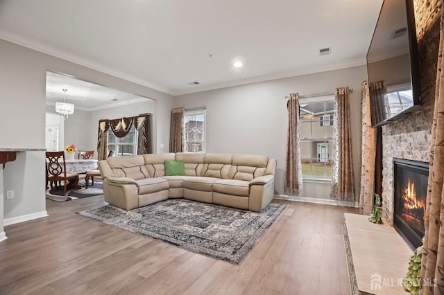 living room featuring wood-type flooring, ornamental molding, a large fireplace, and a healthy amount of sunlight