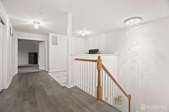 corridor with dark wood-type flooring and a chandelier