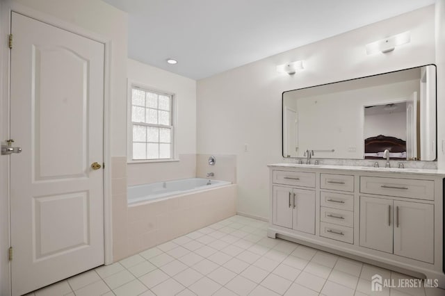 bathroom featuring tiled tub, vanity, and tile patterned flooring