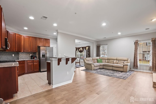 kitchen featuring appliances with stainless steel finishes, backsplash, a center island, light hardwood / wood-style floors, and a kitchen bar