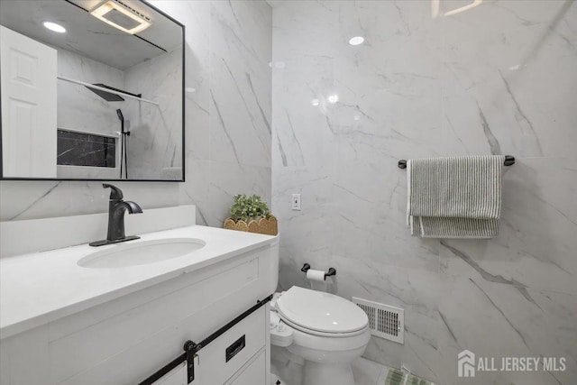 bathroom featuring vanity, tile walls, and toilet