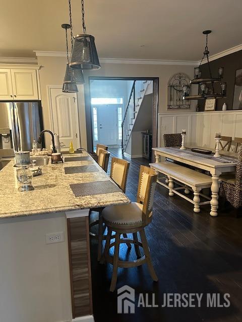 138 N Grabowski Dr Unit 1490, Sayreville, NJ 08859 - kitchen with stainless steel fridge, crown molding, a kitchen breakfast bar, light stone counters, and wood finished floors