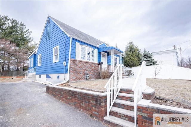 bungalow-style house featuring brick siding, a shingled roof, and fence