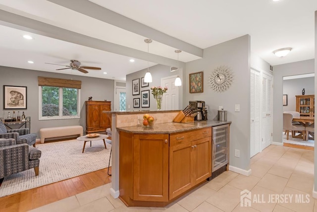16 Russet Rd, South Brunswick, NJ 08824 - kitchen with wine cooler, open floor plan, light stone counters, brown cabinetry, and decorative light fixtures