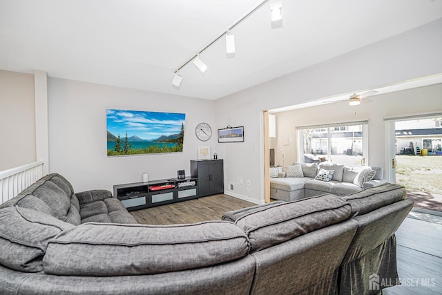 living area featuring rail lighting, ceiling fan, wood finished floors, and vaulted ceiling