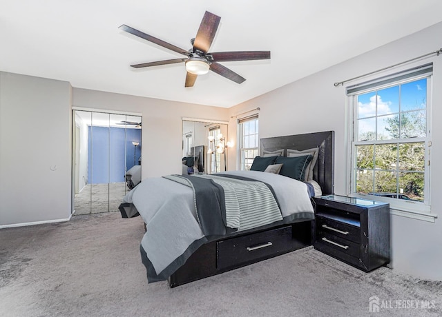 carpeted bedroom featuring two closets, ceiling fan, and baseboards