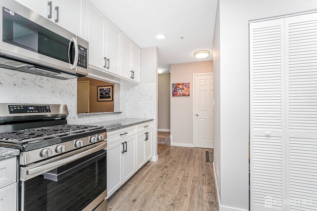 kitchen with decorative backsplash, light wood-style floors, baseboards, white cabinetry, and stainless steel appliances