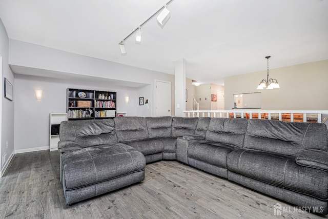 living area with track lighting, baseboards, wood finished floors, and a chandelier