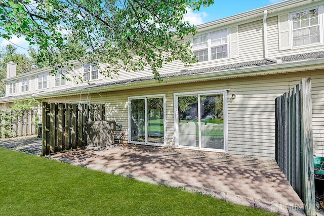 rear view of property with a lawn, a chimney, and a patio area