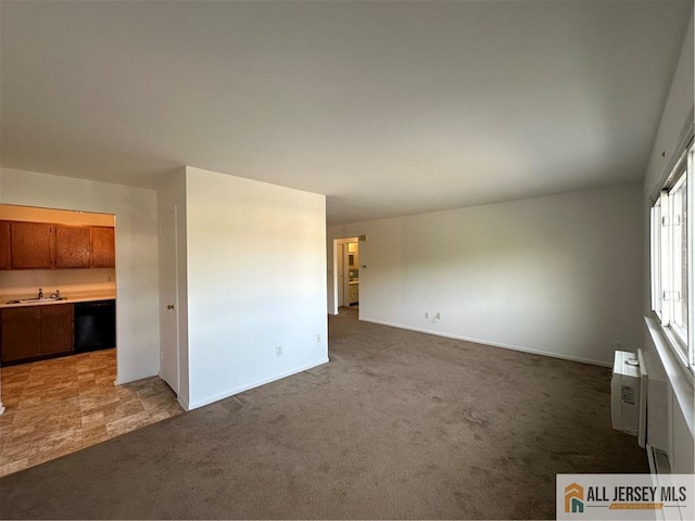 unfurnished living room with light carpet, a sink, baseboards, and a wall mounted AC