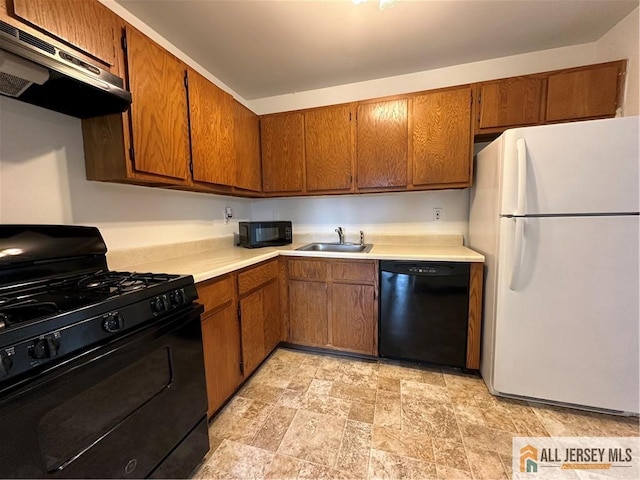 kitchen with black appliances, under cabinet range hood, light countertops, and a sink