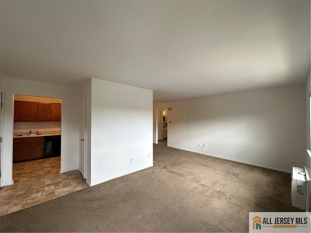 carpeted spare room with a sink and baseboards