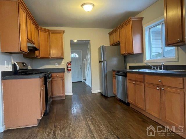 kitchen featuring appliances with stainless steel finishes, dark countertops, and brown cabinets