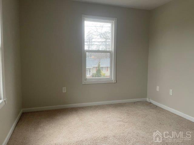 carpeted empty room with baseboards